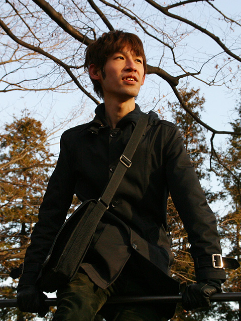 高井 実の顔写真。晴れた空の下、黒一色の服装で公園の鉄棒の上に跨って手前側を見ている。